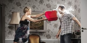 woman thowing a bucket of water at her partner